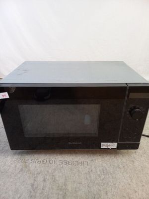 un four à micro-ondes noir posé à même le sol dans une pièce