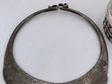 a silver necklace sitting next to a silver bowl on a table