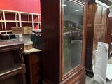a tall wooden cabinet with a glass door in a room