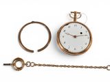 une montre de poche en or et une chaîne posées sur une surface blanche
