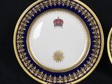 two plates with gold and blue designs are on a black surface