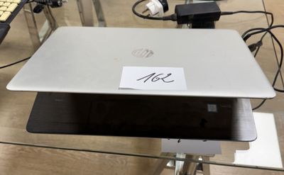 un ordinateur portable sur lequel est collé un autocollant, posé sur une table en verre