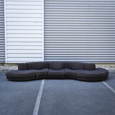 a large black couch sitting in a parking lot next to a building