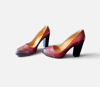 une paire de chaussures rouges et noires posées sur une surface blanche