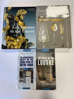 trois livres posés sur une table blanche, avec une statue dorée en arrière-plan
