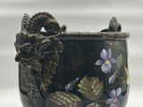 a black vase with purple flowers and a bird on it