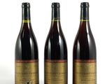 trois bouteilles de vin posées les unes à côté des autres sur une surface blanche