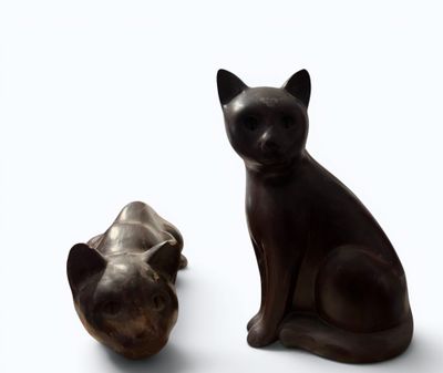 two statues of cats sitting next to each other on a white surface