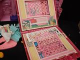 a pink doll house with a pink suitcase on a table