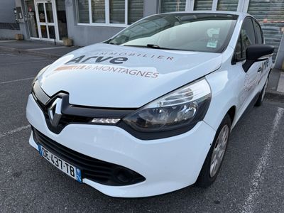 La voiture blanche est garée devant un immeuble sur lequel est accrochée une pancarte.