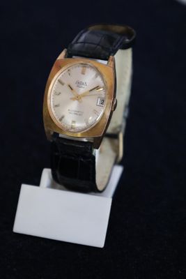 an image of a gold and black watch on a stand