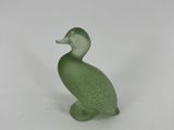 a green glass duck figurine sitting on a white surface