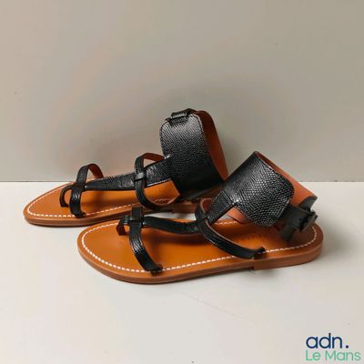 sandales en cuir noir avec des lanières noires sur un fond blanc