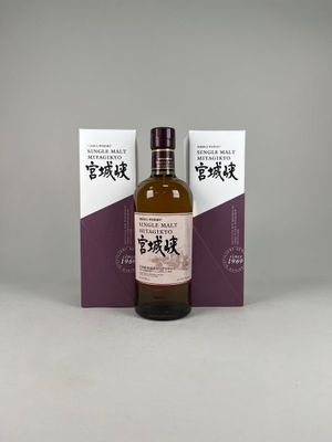 une bouteille de whisky posée sur une table à côté d'un coffret