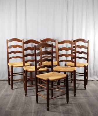 quatre chaises en bois sont alignées contre un rideau blanc