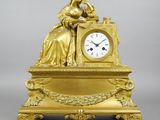 une horloge en or avec une femme assise dessus