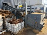 un gros tas de bois dans un conteneur à côté d'un bâtiment