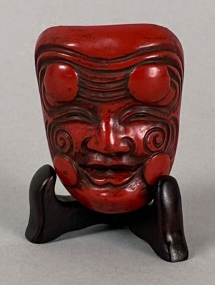 a small red sculpture of a face on a stand