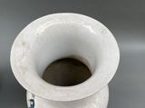 a white vase sitting on a table next to a black vase