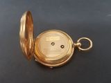an image of a gold pocket watch sitting on a black surface