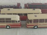 quatre petits bus en jouet posés les uns à côté des autres sur une table