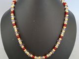 a red and gold beaded necklace on a black mannequin
