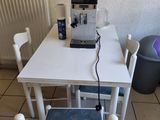 une petite table sur laquelle se trouvent deux chaises et une cafetière