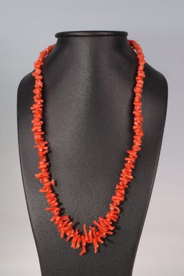 un collier composé de perles de corail, présenté sur un mannequin noir