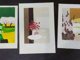 three cards with paintings of trees and flowers on them on a black surface