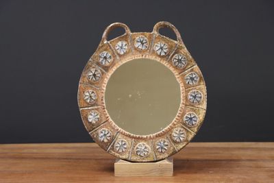 un petit miroir posé sur un socle en bois, sur une table