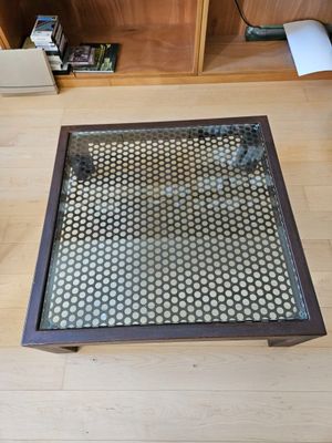 a coffee table with a glass top sitting on a wooden floor