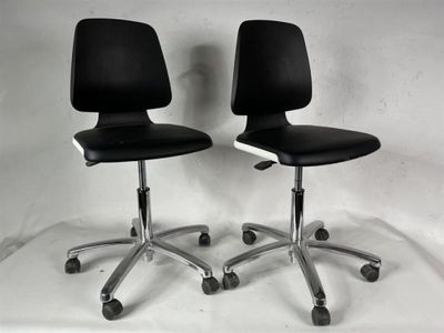 une paire de chaises de bureau noires sur roulettes, devant un fond blanc