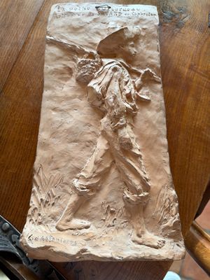 une figurine en papier mâché représentant un homme assis sur une table, tenant une paire de ciseaux