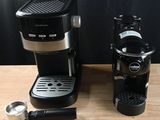 a black coffee maker and a silver coffee cup on a wooden table