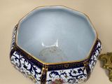 a blue and white bowl sitting on a table next to a gold object