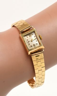 une photo du poignet d'une femme portant une montre en or