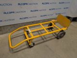 a yellow hand truck that is sitting in front of a wall