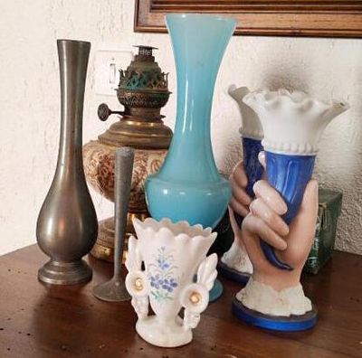 plusieurs vases posés sur une table en bois, avec un tableau en arrière-plan