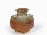 un petit vase posé sur une surface blanche