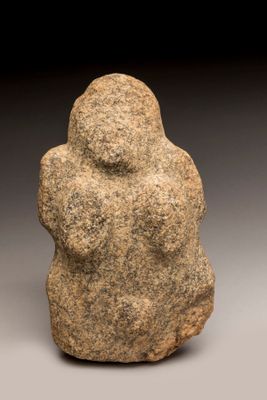 un gros plan sur une statue en pierre représentant une personne, posée sur une surface grise