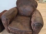 un fauteuil et un pouf en cuir marron dans un salon