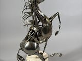 statue of a horse on a pedestal with a bell in its mouth