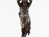 une statue en bronze représentant une femme tenant un panier sur la tête