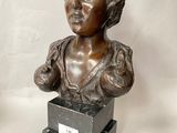 bronze bust of a woman in a dress sitting on a pedestal
