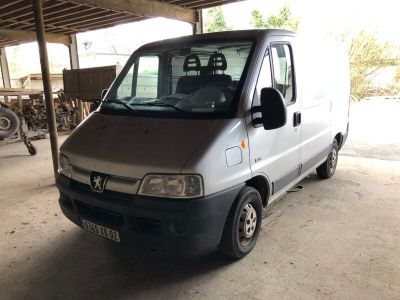 une camionnette argentée garée dans un garage, avec une moto en arrière-plan