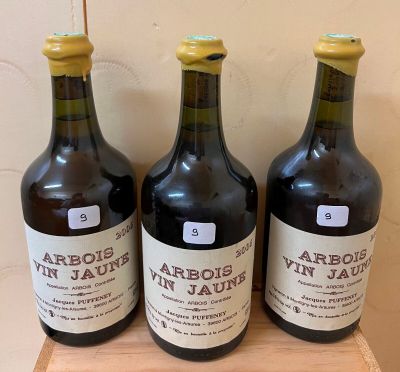 three bottles of wine sit on a wooden shelf in front of a wall