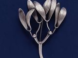 une image représentant une broche en argent ornée de fleurs sur fond bleu