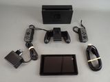 une console Nintendo Wii posée sur une table, à côté d'un chargeur et d'autres accessoires
