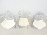 three chairs and a table in a room with a white wall