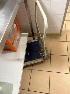 tiled floor in a commercial kitchen with a scale on the floor